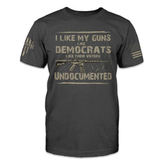 An asphalt-gray t-shirt which has a design on the front "I like my guns like democrats like their voters: undocumented," with an AR-15 rifle.