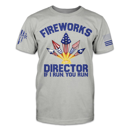 A light grey t-shirt with an image of fireworks on the front with the words "Fireworks Director - I run, you run"