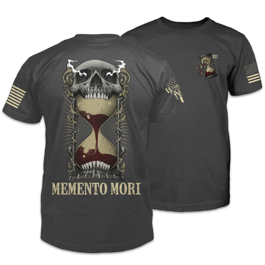 The front and back of an asphalt-gray t-shirt with an image on the back of an hourglass filled with red sand in the mouth of a human skull and the words "Memento Mori" underneath. The front of the shirt has a small pocket image of a broken hourglass.