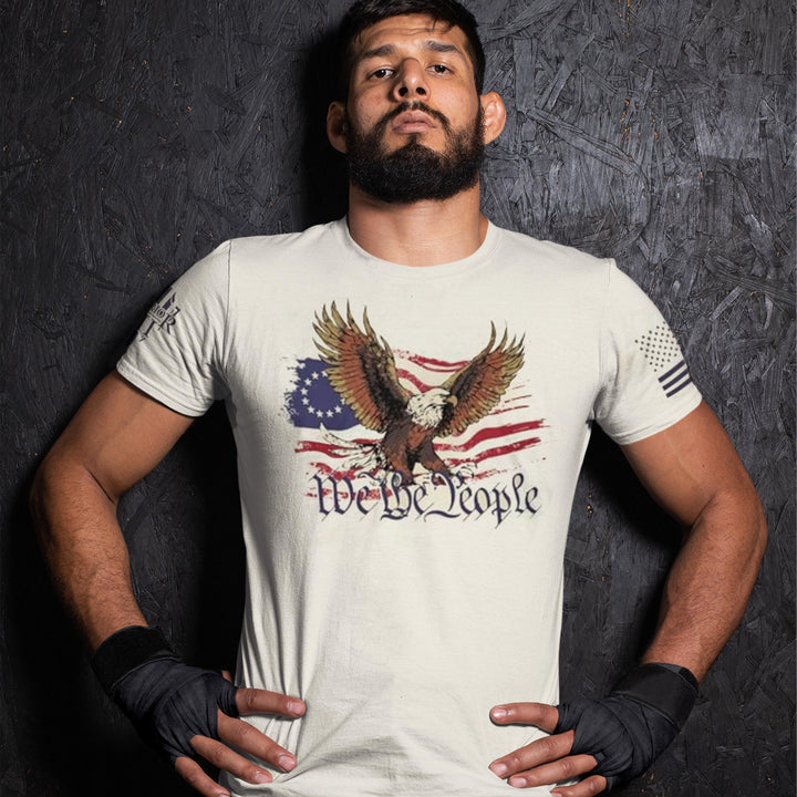 "We The People" is printed on a natural color t-shirt with the main design printed on the front and the back of this t-shirt has no printing. This shirt features our brand logo on the right sleeve and the American Flag on the left sleeve.