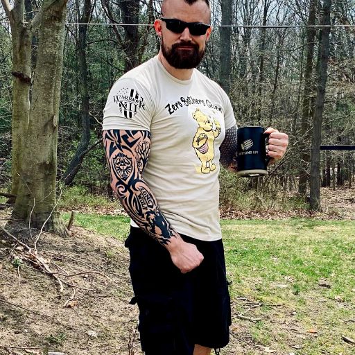 One of our awesome customers enjoying a hot cup of coffee outdoors while wearing our Zero Bothers Given t-shirt. 