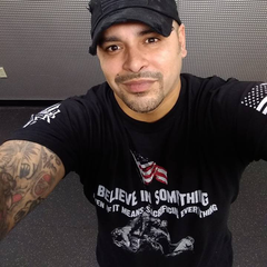 A customer wearing a black t-shirt with the words "Believe In Something, Even If It Means Sacrificing Everything" with soldiers putting up the American flag printed on the front of the shirt.