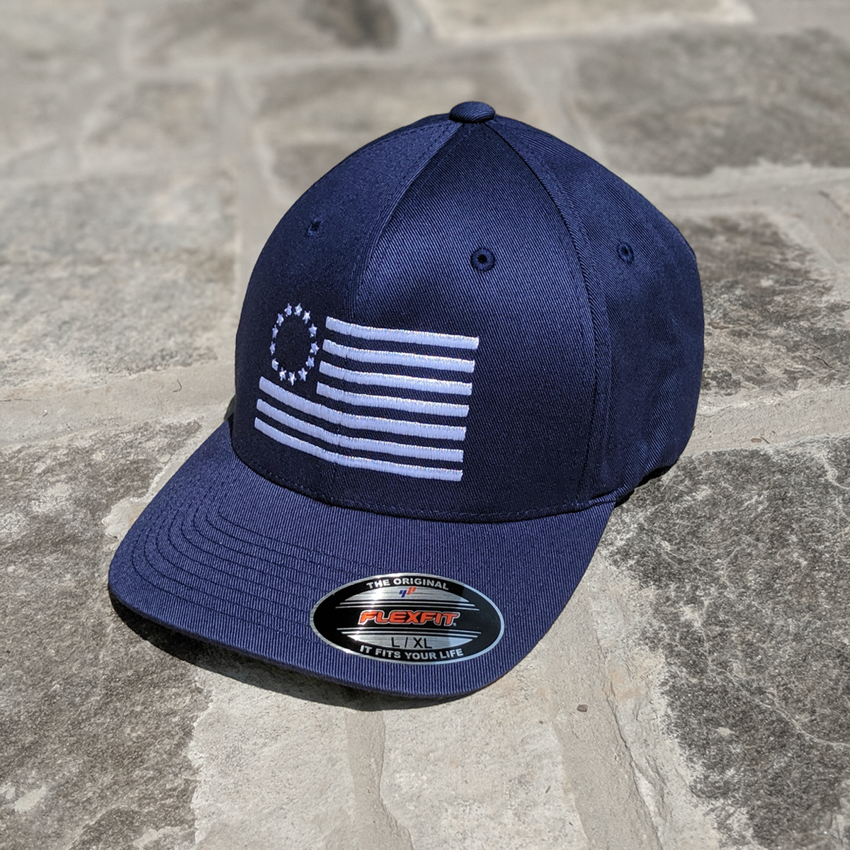 Betsy Ross Flag Flexfit features the Betsy Ross Flag embroidered on a blue flexfit hat.