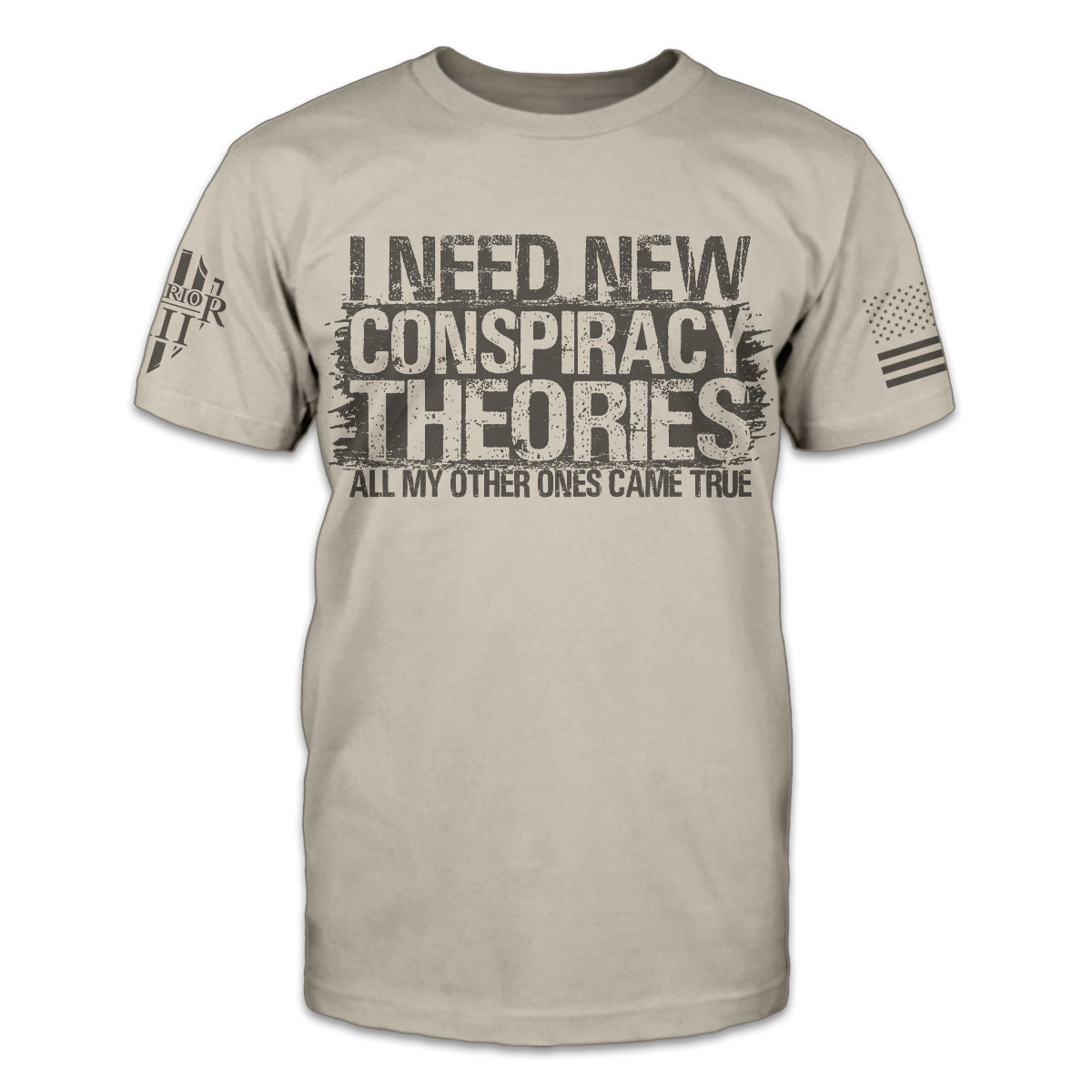 A light tan t-shirt with the words 'I need new conspiracy theories, all my other ones came true" printed on the front of the shirt.