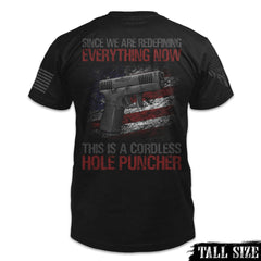 A black tall sized shirt with the words "Since we are redefining everything now, this is a cordless hole puncher", with a pistol printed on the back of the shirt.