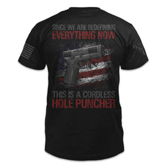 A black t-shirt with the words "Since we are redefining everything now, this is a cordless hole puncher", with a pistol printed on the back of the shirt.