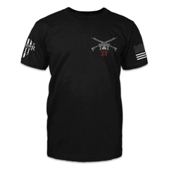 A black t-shirt with two guns crossed over with the roman numerals XII printed on the front of the shirt.