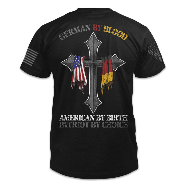 A black t-shirt with the words 'German by blood, American by birth, patriot by choice" and a cross with the German and USA flag hanging over it printed on the back of the shirt.