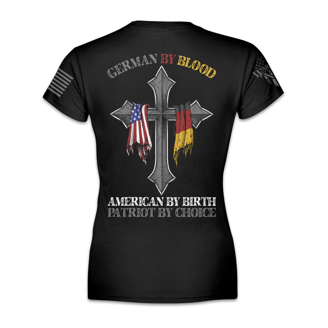 A black women's relaxed fit'shirt with the words 'German by blood, American by birth, patriot by choice" and a cross with the German and USA flag hanging over it printed on the back of the shirt.