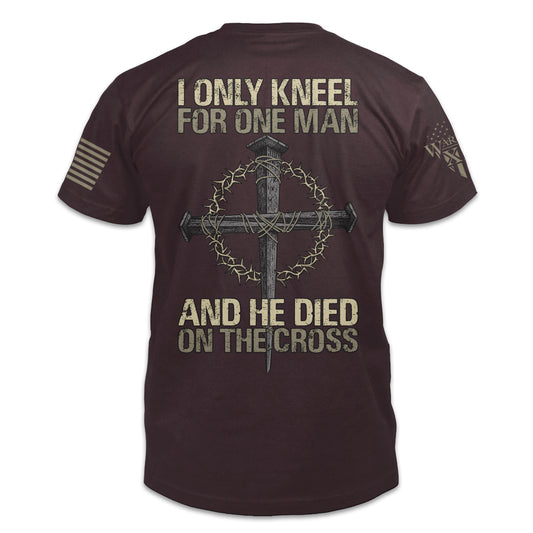 A burgundy t-shirt with the words "I only kneel for one man, and he died on the cross" with a cross printed on the back of the  shirt.