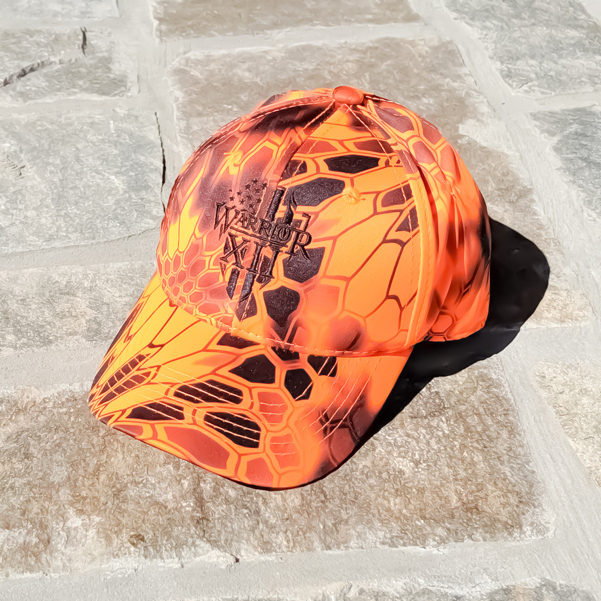 A Warrior hat that features the Warrior 12 shield embroidered on a Kryptek Inferno camo strapback.