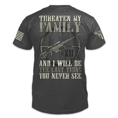 A grey t-shirt with the words "Threaten My Family and I'll Be The Last Thing You Never See" and a gun printed on the back of the shirt.