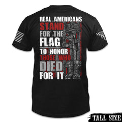 A black tall size shirt with the words "Real Americans Stand For The Flag To Honor Those Who Died For It!" printed on the back of the shirt.