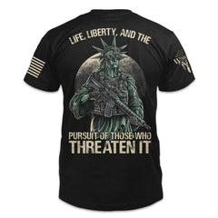 A black t-shirt with the words "Life, liberty, and the pursuit of those who threaten it" with the statue of liberty holding a gun printed on the back of the shirt.
