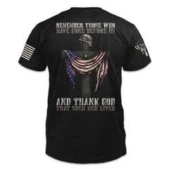 A black t-shirt with the words "Remember those who have gone before us, and thank God that such men lived" with a cross holding a helmet and American flag printed on the back of the shirt.