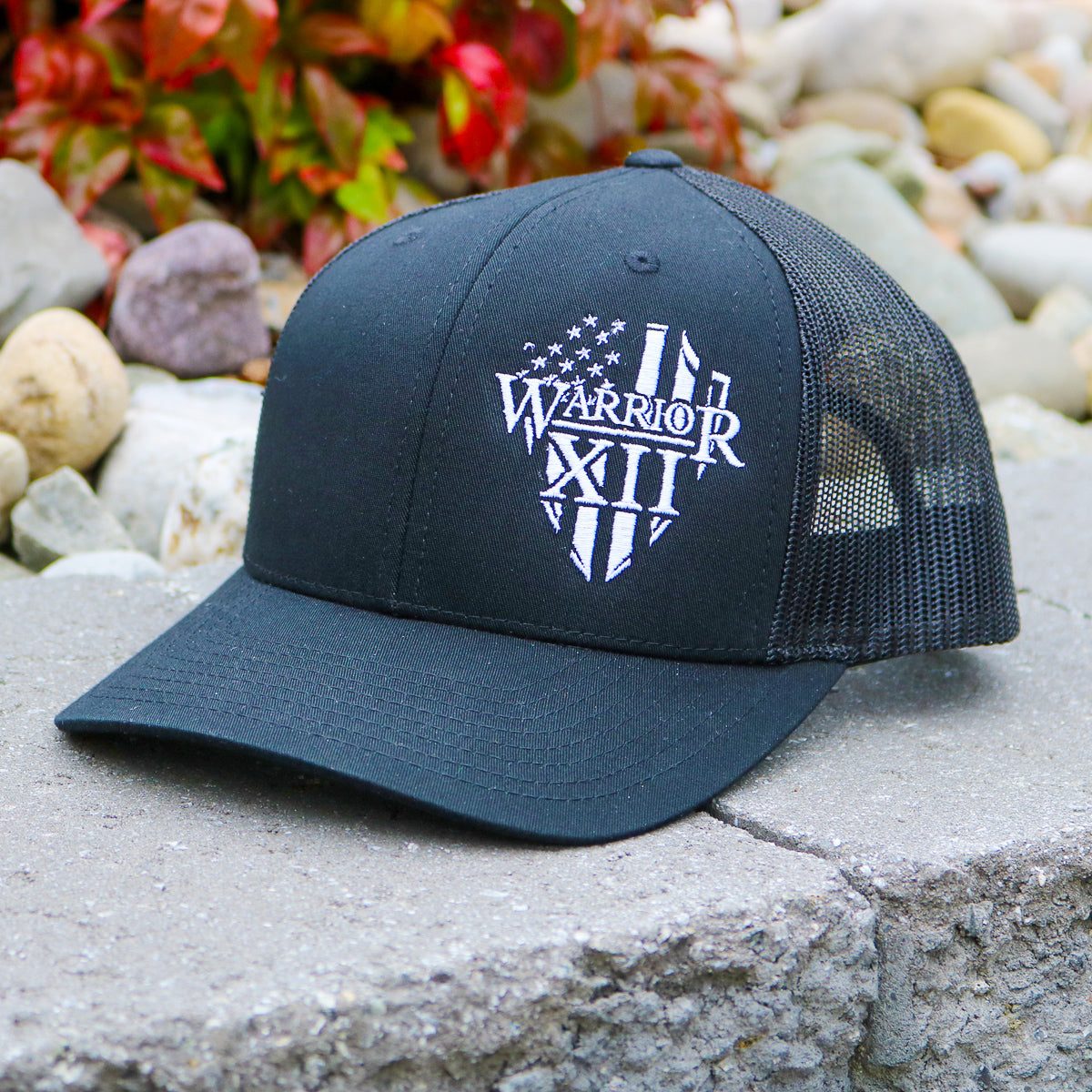 A Warrior 12 hat features the Warrior 12 shield embroidered on a black Richardson mesh snapback hat.