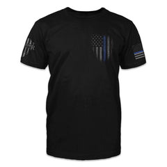 A black t-shirt with a distressed thin blue line USA flag printed on the front left chest.