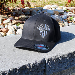 A Flexfit hat that features the Warrior 12 shield embroidered on a black flexfit hat.