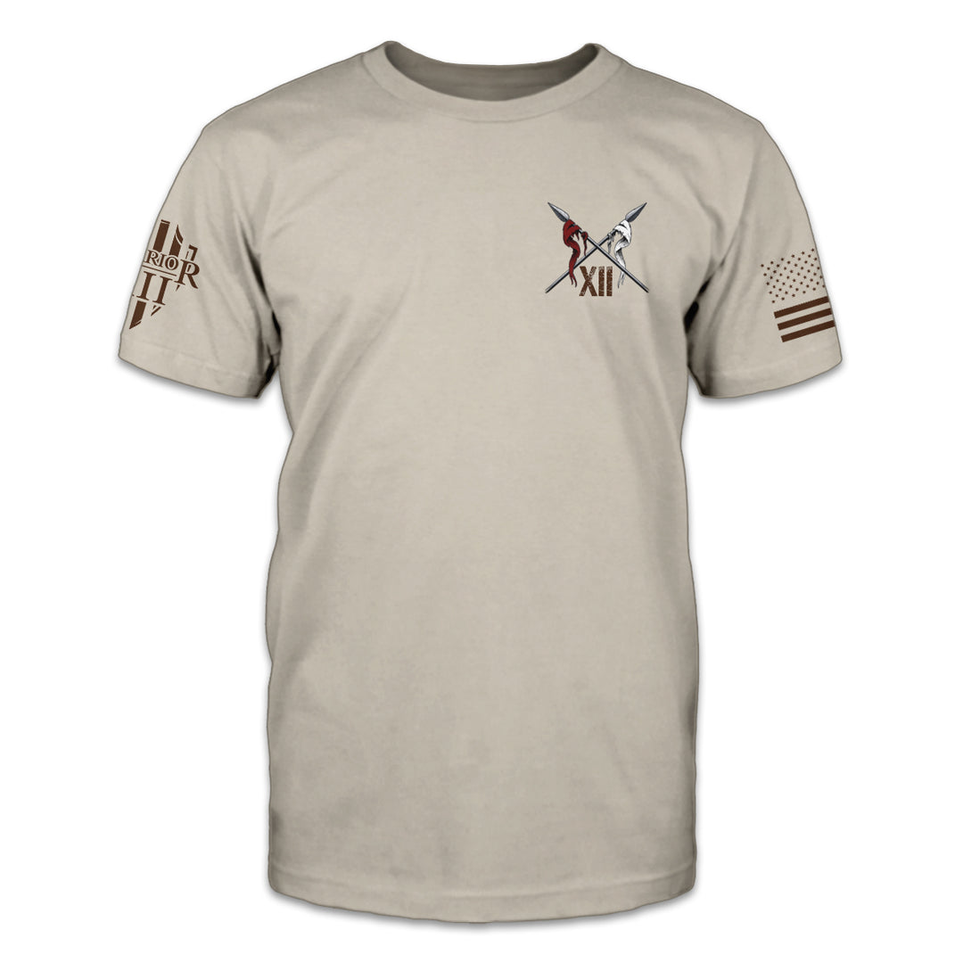 A light tan t-shirt with two spears crossed over printed on the front of the shirt.